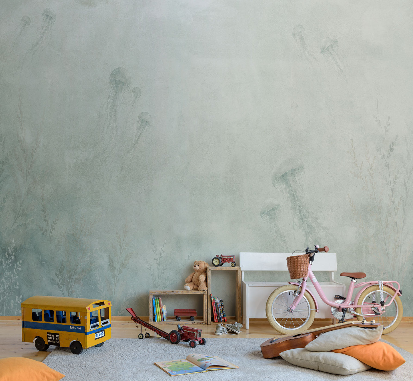 Kinderzimmer mit rosa Fahrrad, gelbem Spielzeugbus, Holzregal, Kuscheltier und Kissen vor einer Tapete mit dezentem Quallenmuster von Superwalls
