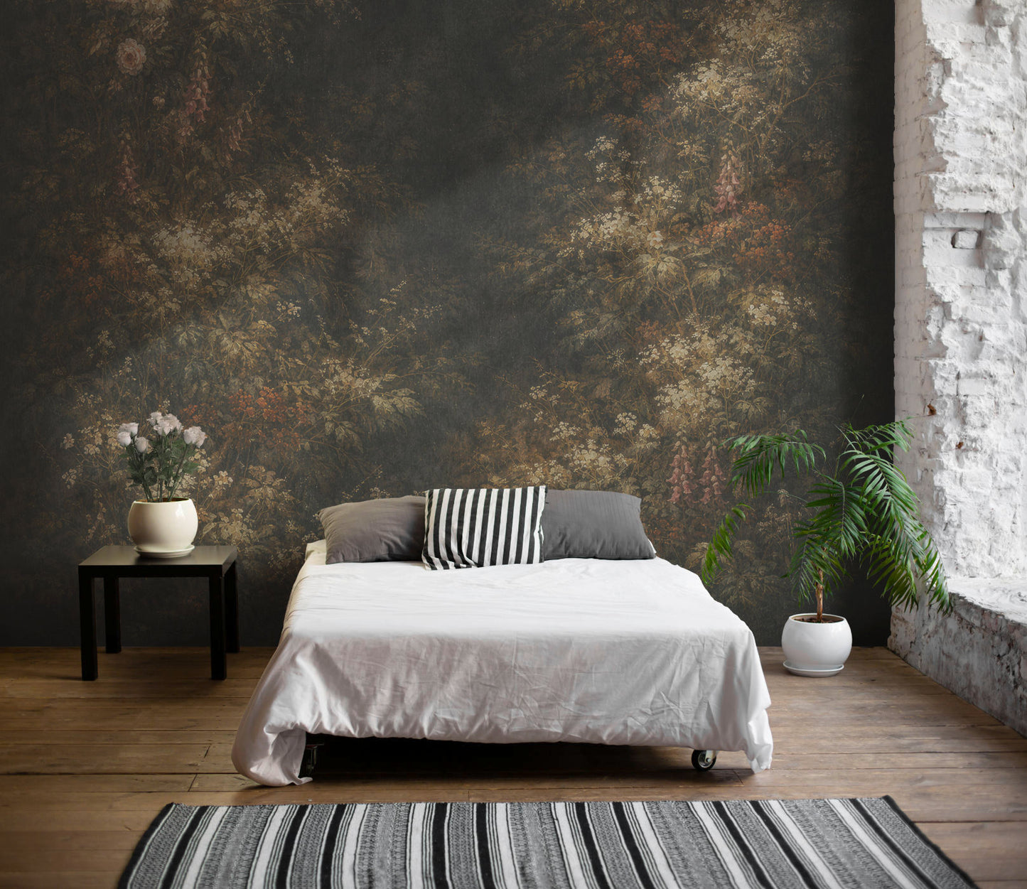 Schlafzimmer mit Doppelbett vor einer Wand mit floralem Vliestapete von Superwalls, links ein Beistelltisch mit Vase und Blumen, rechts zwei Pflanzen in weißen Töpfen, Holzboden und gestreifter Teppich im Vordergrund
