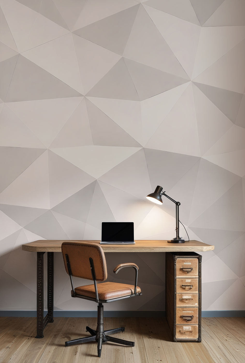 Schreibtisch mit Laptop, Schreibtischlampe und braunem Bürostuhl vor einer Tapete von Superwalls mit geometrischem Origami Muster