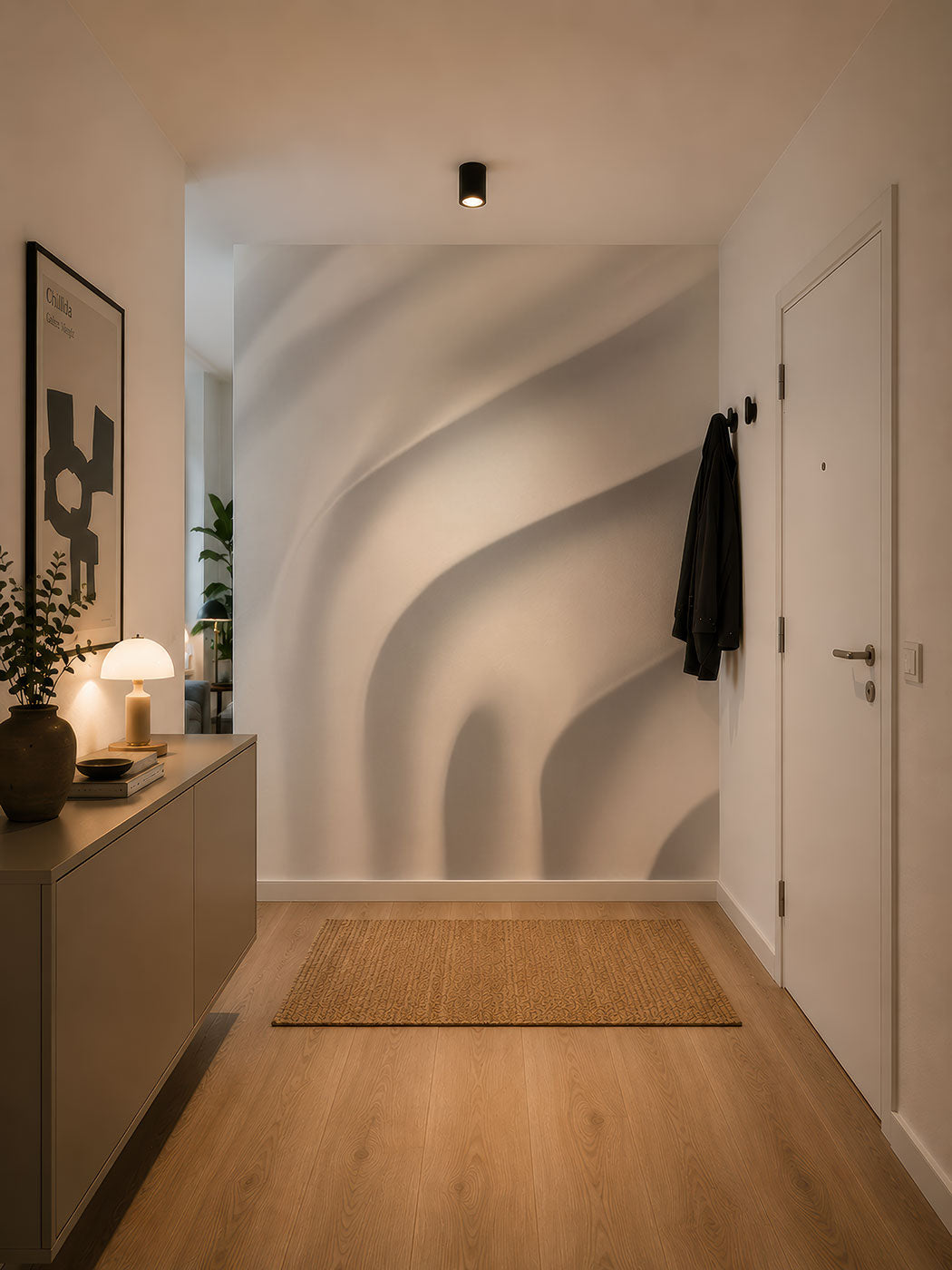 Flur mit hellem Holzboden, beigeem Teppich, Sideboard mit Lampe und Deko, abstrakter Tapete von Superwalls  und schwarzem Mantel an Wandhaken neben weißer Tür