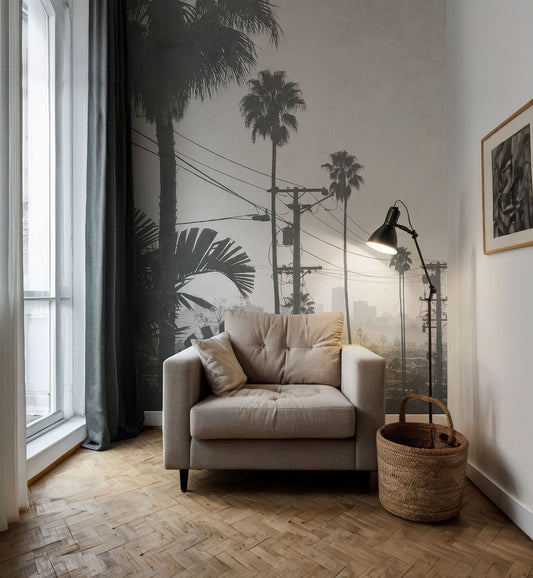 Beiger Sessel mit Kissen vor Wand mit Fototapete von Palmen und Stromleitungen von Superwalls neben Stehlampe und geflochtenem Korb auf Parkettboden