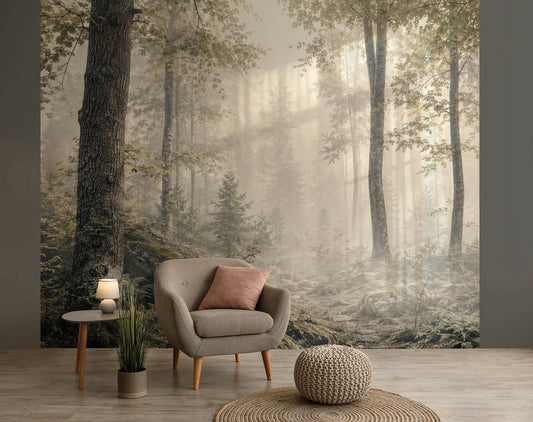 Wohnzimmer mit grauem Sessel, rosa Kissen, kleinem Beistelltisch mit Lampe, Pflanzen und einer Tapete mit nebligem Waldmotiv von Superwalls