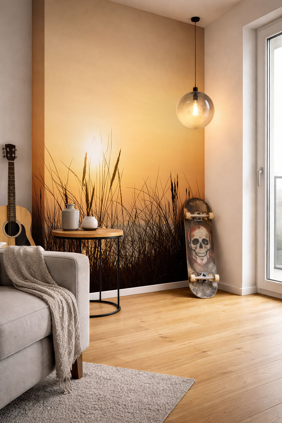Wohnzimmerecke mit grauem Sofa, Beistelltisch, Fototapete mit Gräsern und aufgehender Sonne, Skateboard mit Totenkopfmotiv und hängender Glaskugel-Lampe. Vliestapete von Superwalls