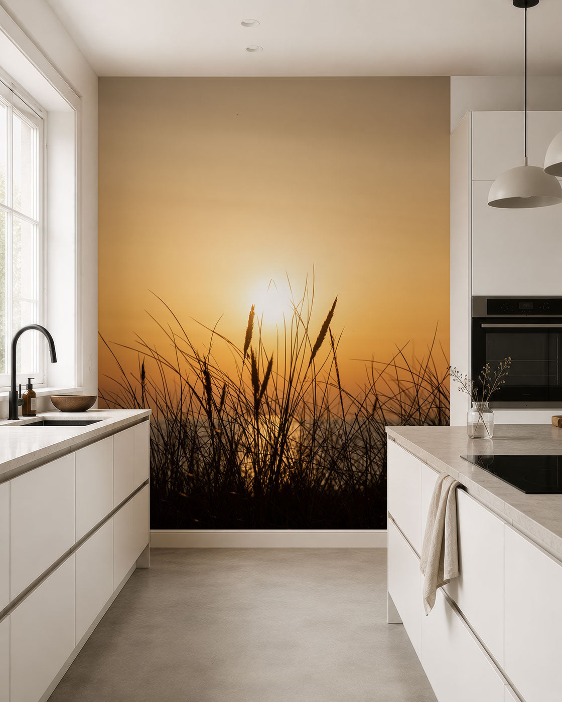 Küche mit weißen Schränken und Arbeitsplatten vor einer Wand mit Fototapete eines Sonnenuntergangs hinter Gräsern von Superwalls