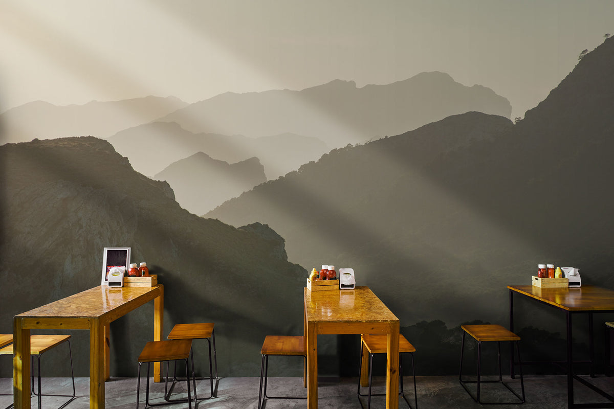 Holztische und -hocker in einem Raum mit einer Tapete, die mehrere Bergsilhouetten in verschiedenen Grautönen zeigt. Vliestapete von Superwalls