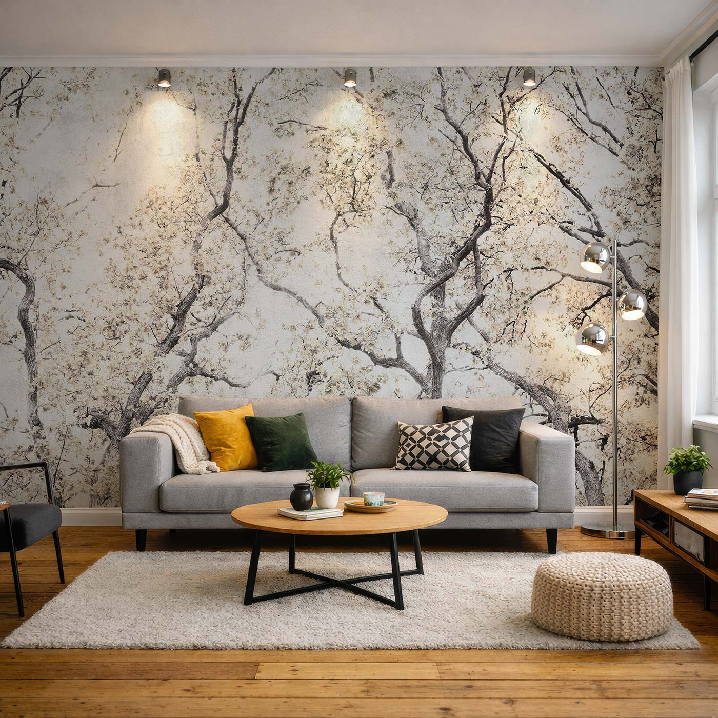 Wohnzimmer mit grauem Sofa, gemusterter Fototapete von Superwalls mit Baumzweigen, rundem Holztisch, Stehlampe mit drei Kugelleuchten und hellem Teppich