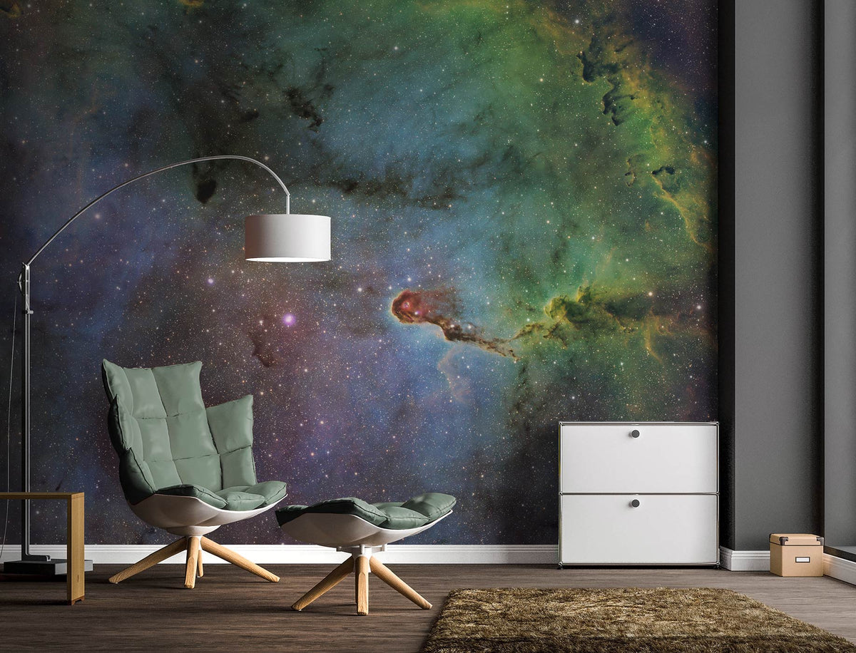 Moderner Wohnraum mit grün gepolstertem Sessel und Hocker vor einer Vliestapete mit Weltraummotiv von Superwalls und weißem Sideboard