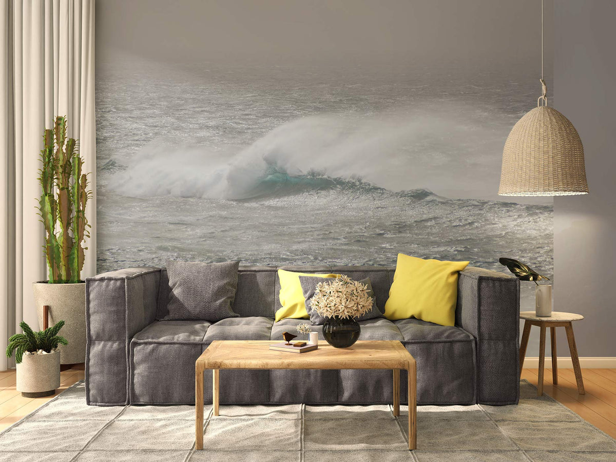 Wohnzimmer mit grauem Sofa, gelben Kissen, Holztisch, Pflanzen und großer Vliestapete mit Meereswellen von Superwalls