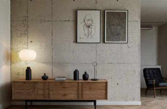 Holzsideboard mit schwarzen Vasen und einer Lampe vor einer Betonwand Fototapete von Superwalls mit zwei gerahmten schwarz-weißen Linienzeichnungen